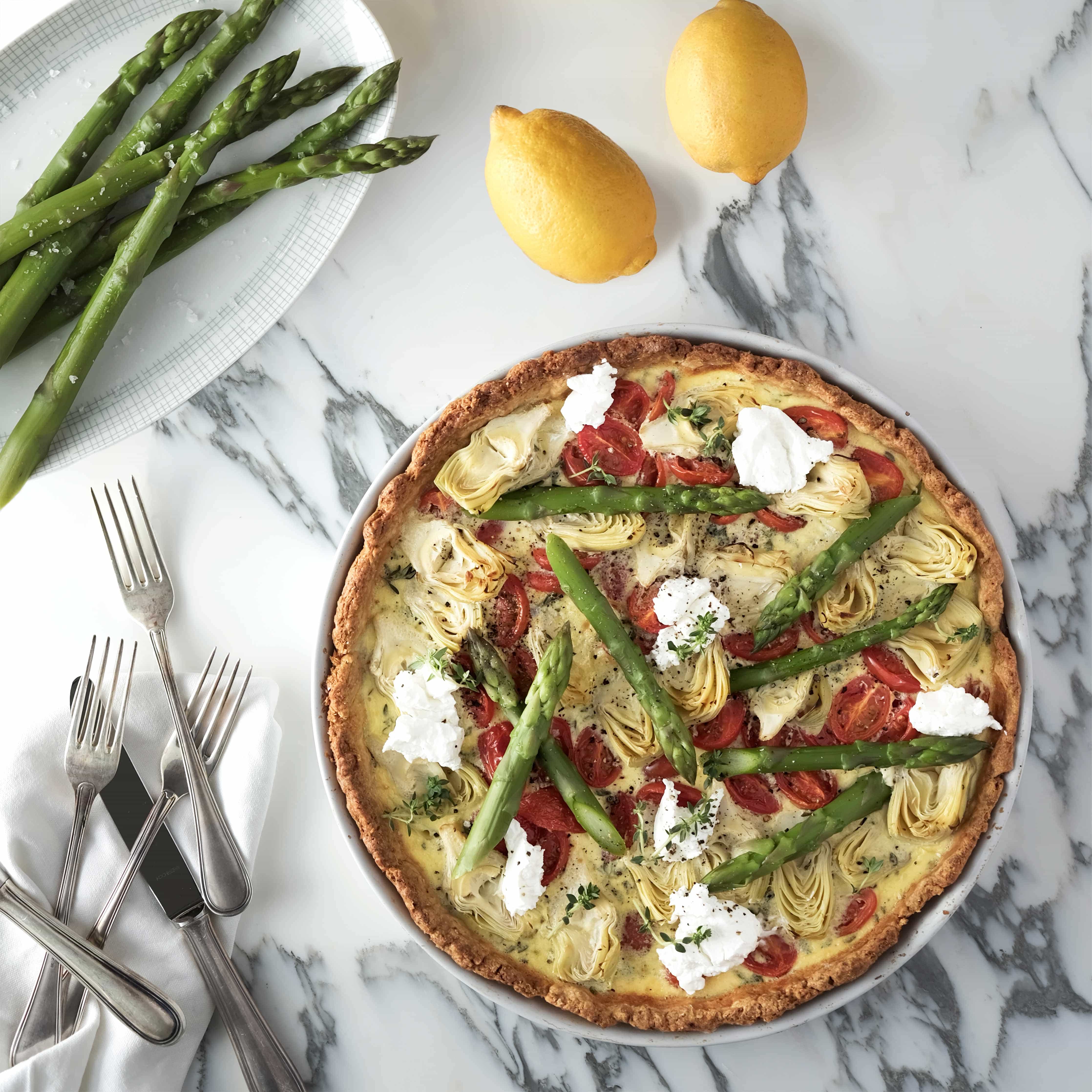 Runder Quiche mit grünen Spargeln, Artischocken auf Marmorplatte serviert