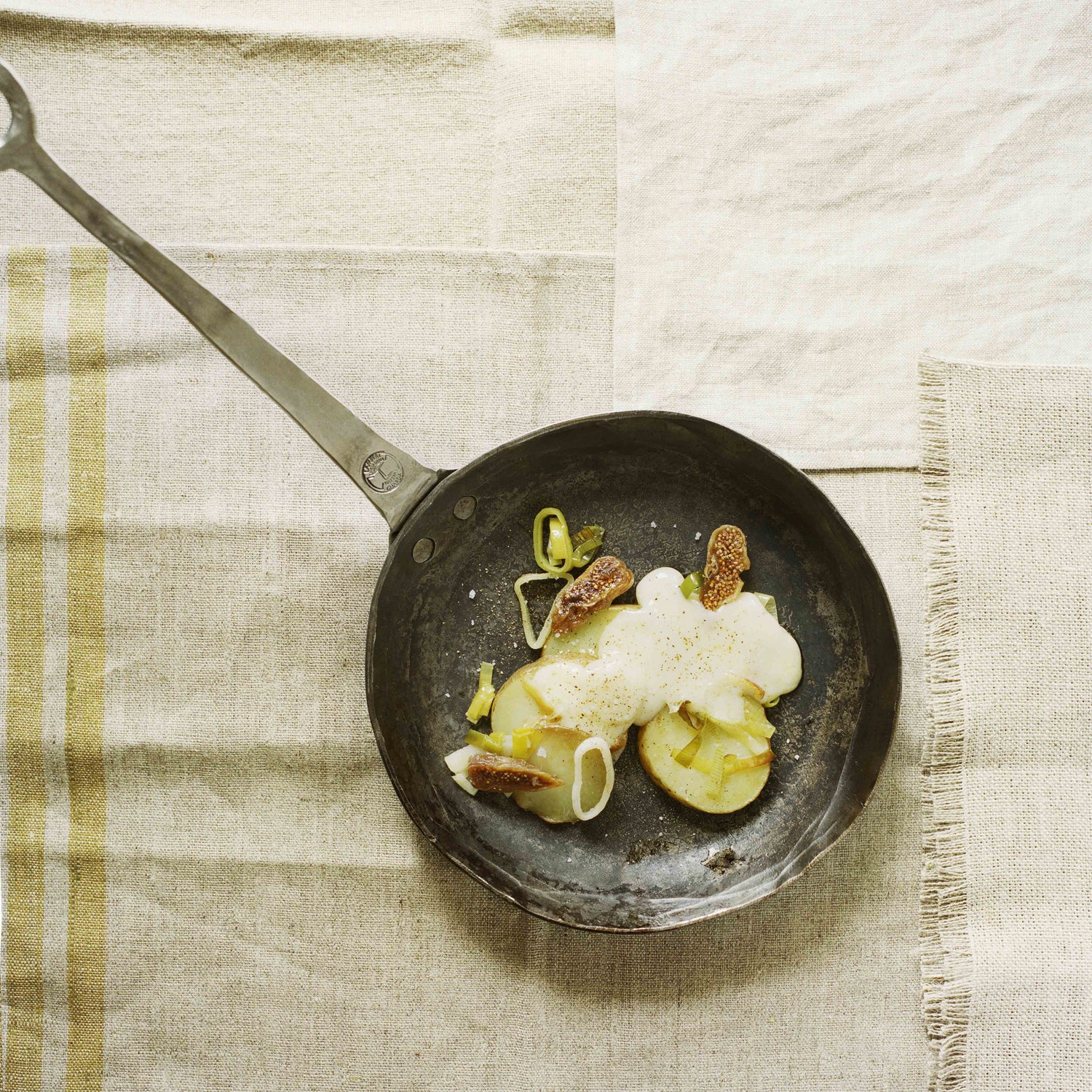 Cholera mit Gschwellti, Äpfel und Dörrfeigen als Pfannenraclette in einer handgeschmiedeten Pfanne von Thomas Lampert angerichtet