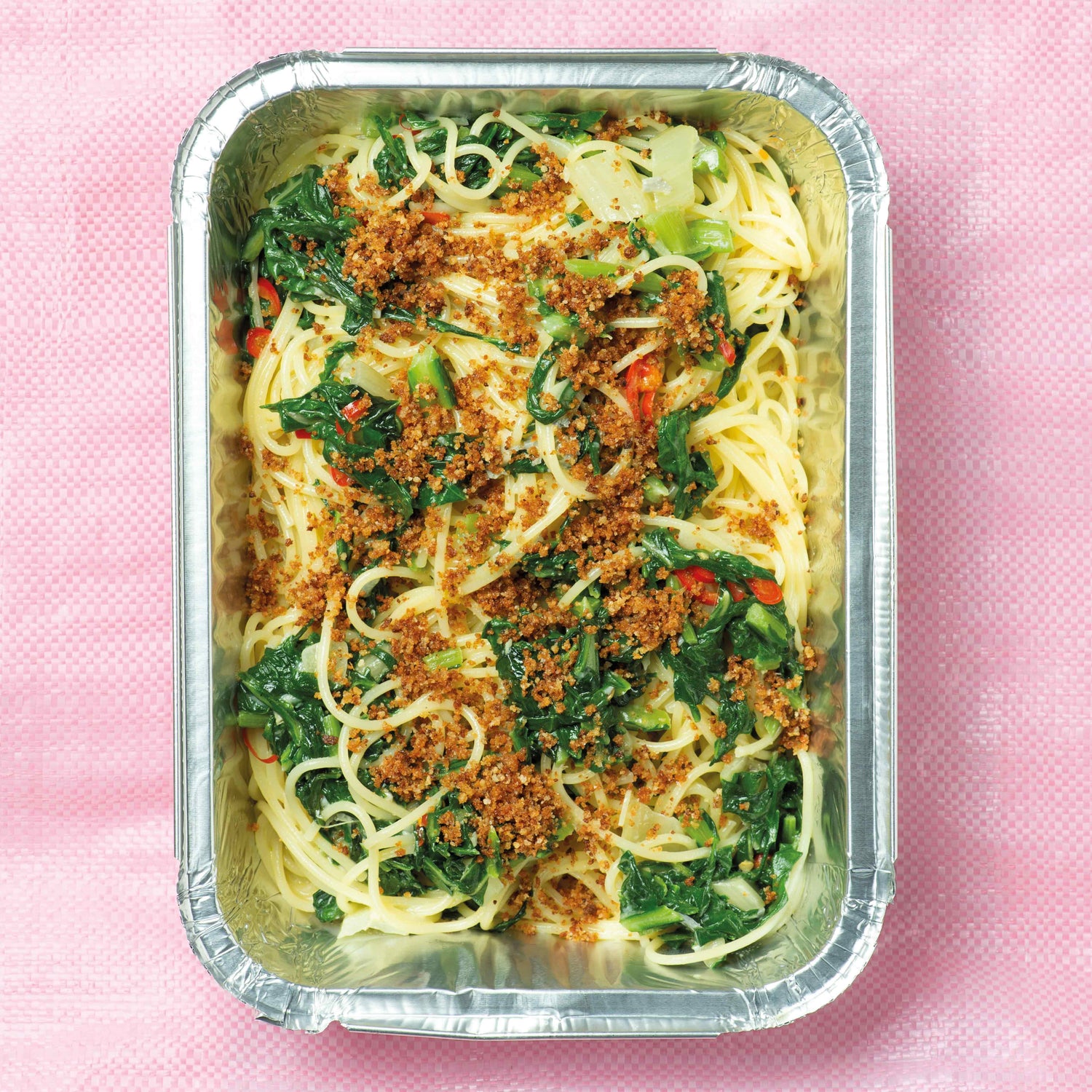 Rechteckige Schale mit Spaghetti, Mangold und Brotbrösel auf rosa Untergrund