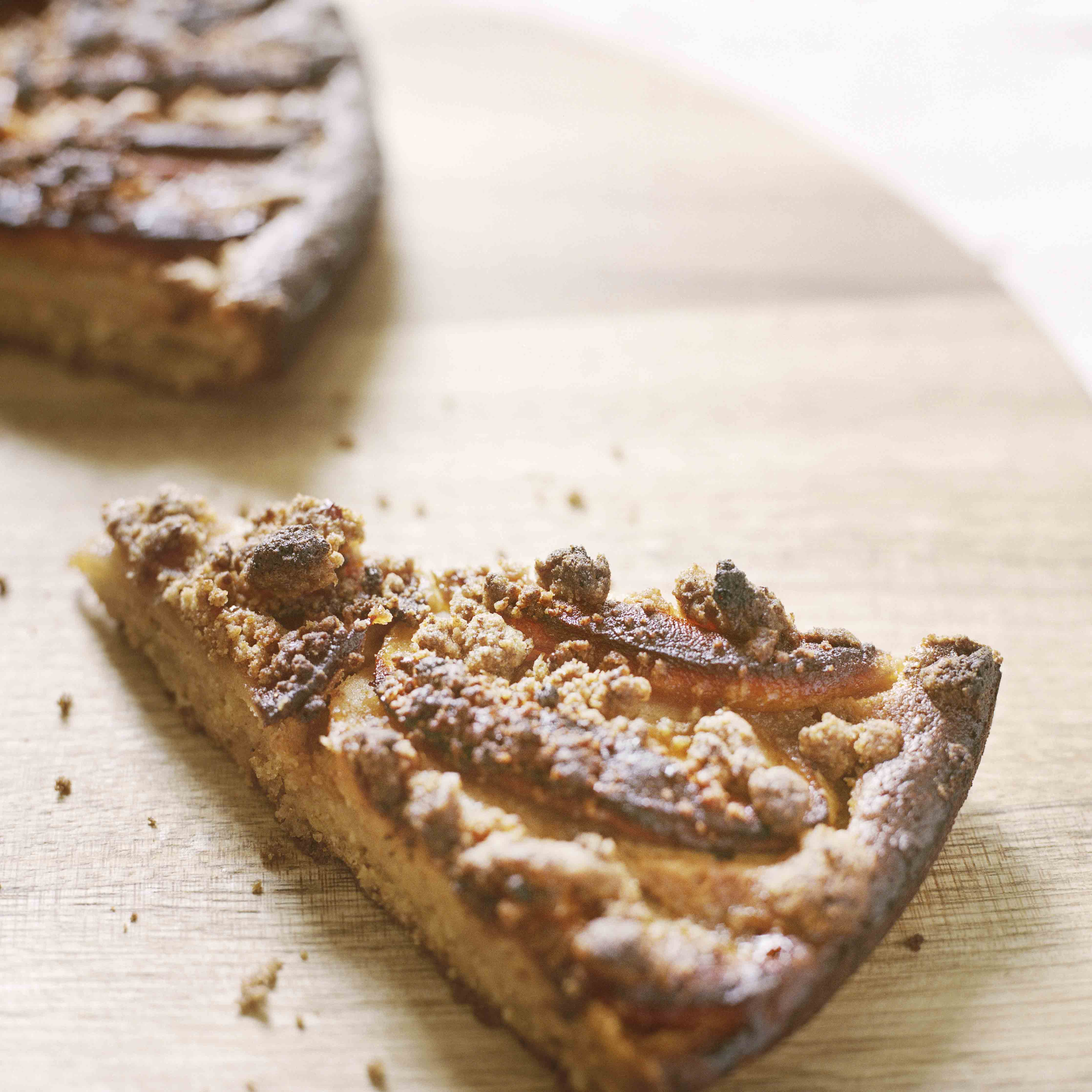Ein Stück Streuselkuchen mit Topinambur als Dessert serviert auf einem runden Holzbrett aus Eiche der Schreinerei Hürst