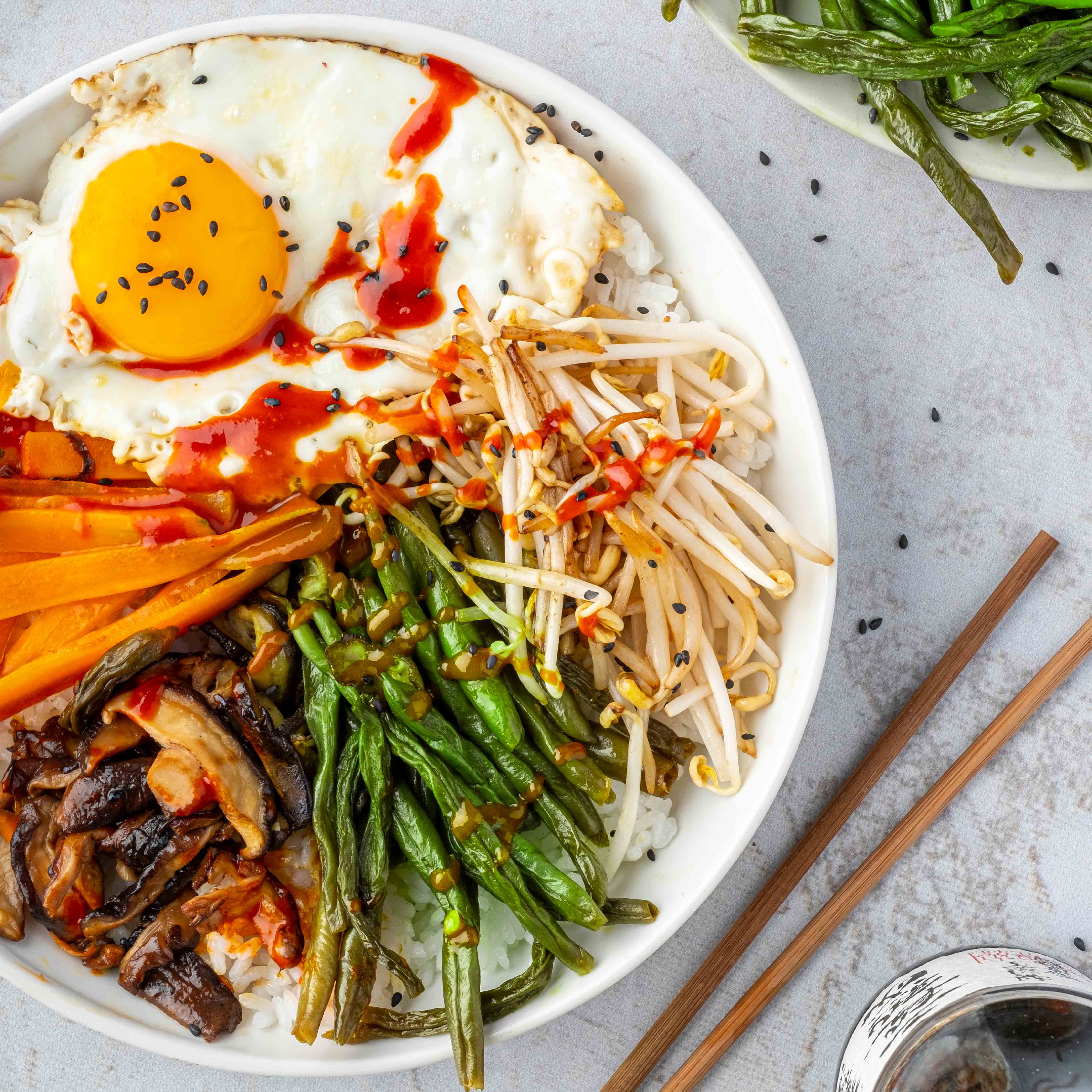 Koreanisches Dörrbohnengericht Bibimbap mit Spiegelei und schwarzem Sesam