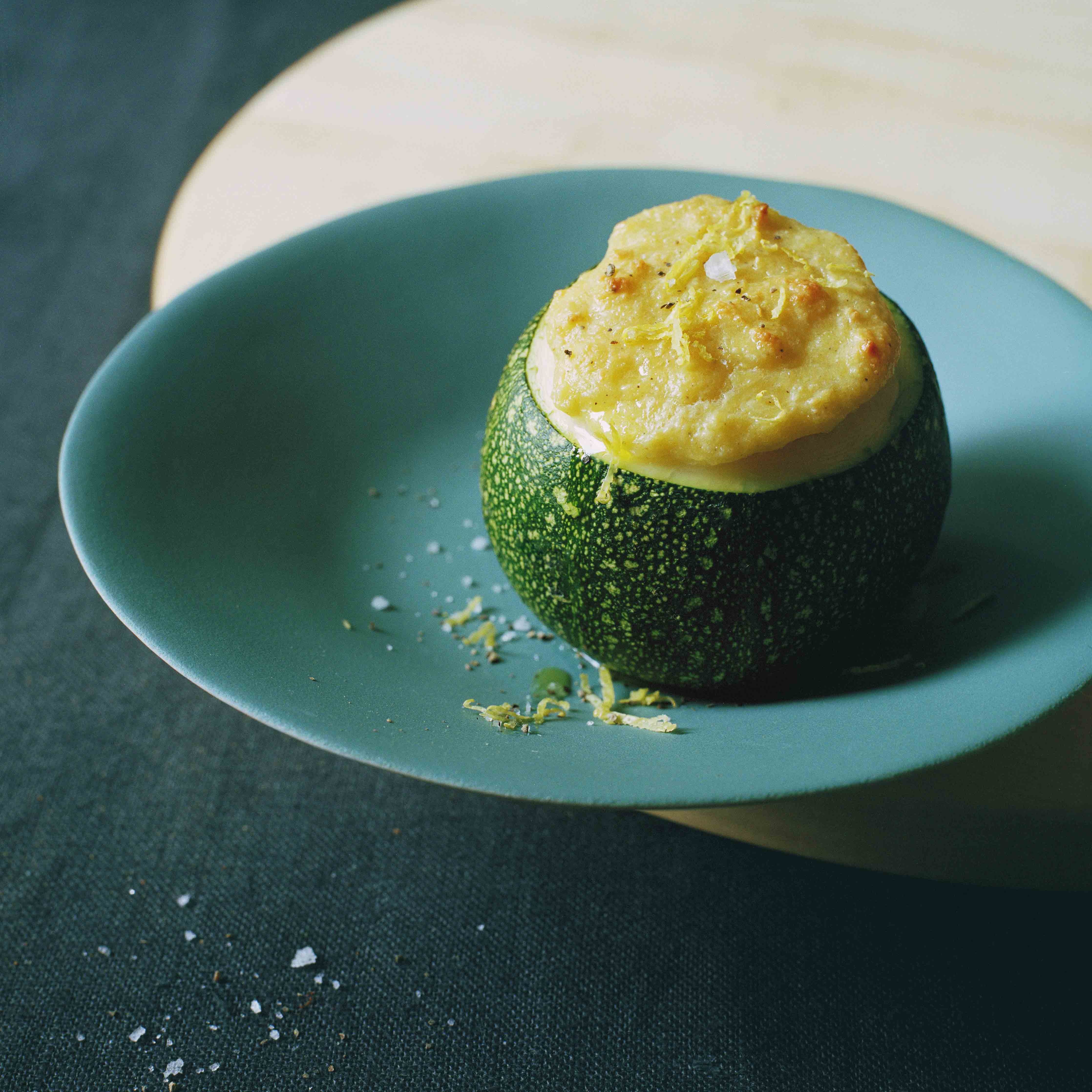 Runde Zucchini mit Griess-Ricotta-Füllung angerichtet auf einem Holzbrett von Hürst und garniert mit Salzflocken von Nordur