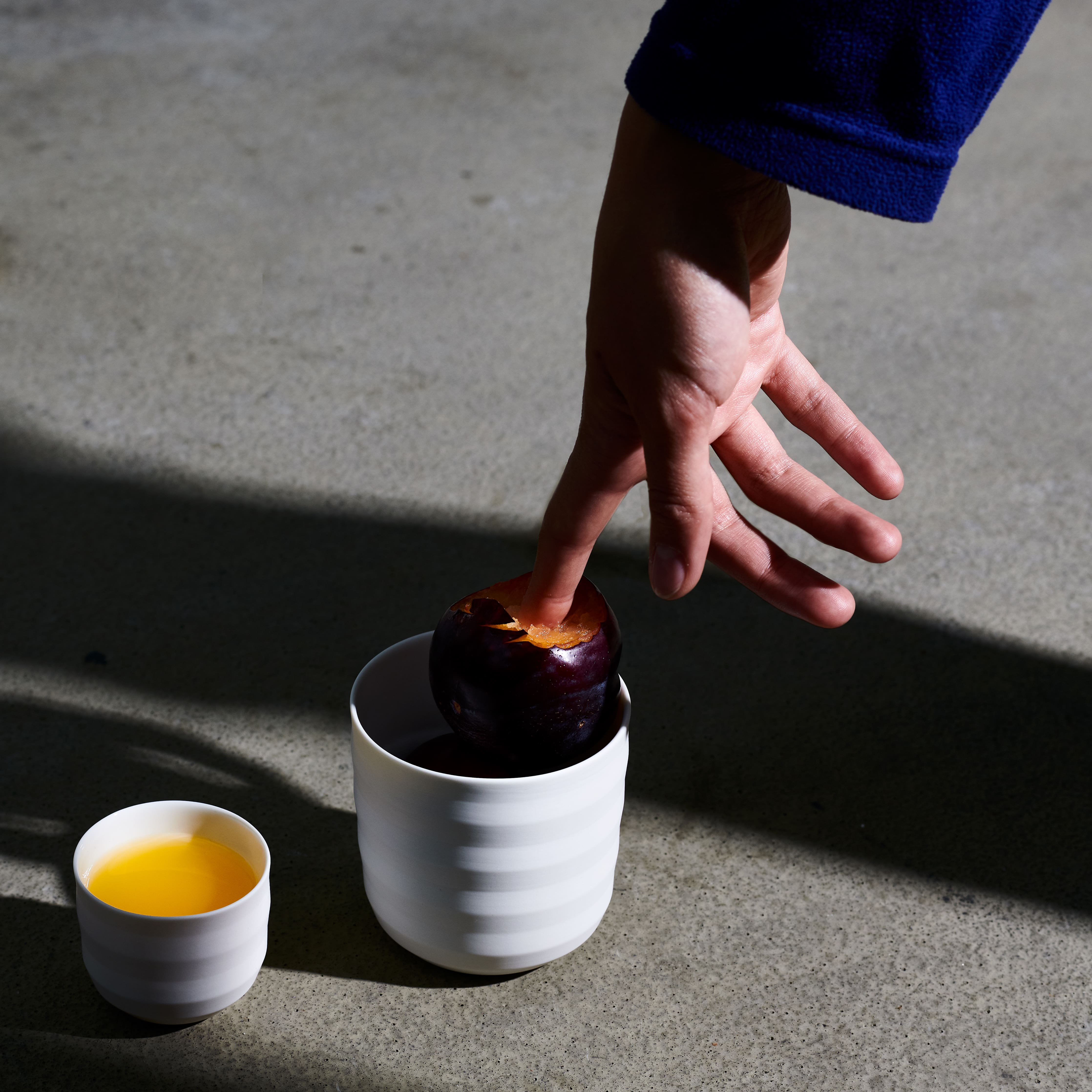 mood: Moodbild zweier Becher der DB20 Serie auf Asphalt und einer Hand mit starkem Licht-Schatten
