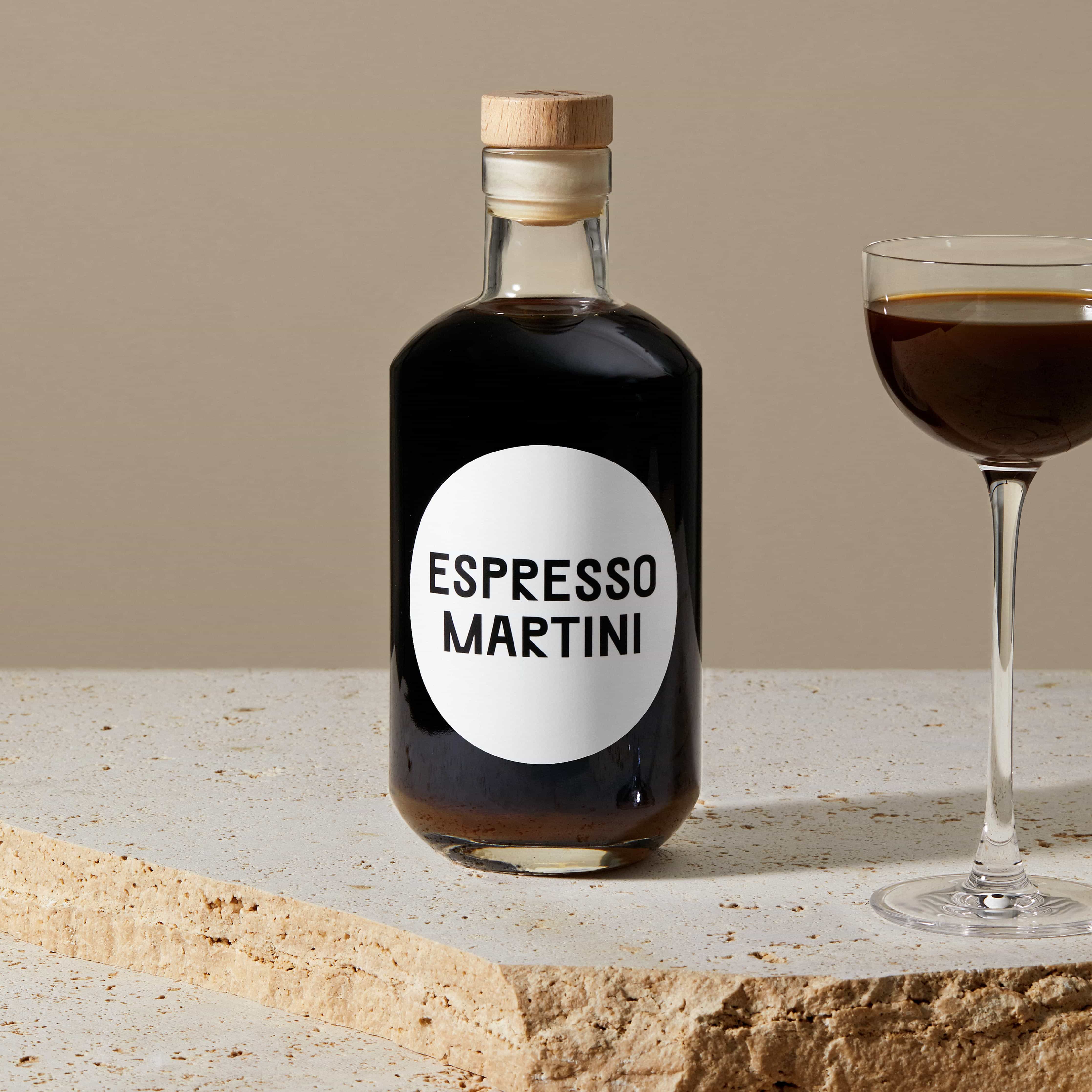 mood: Stimmungsbild der Espresso Martini Flasche auf Travertin neben einem Cocktailglas mit Espresso Martini