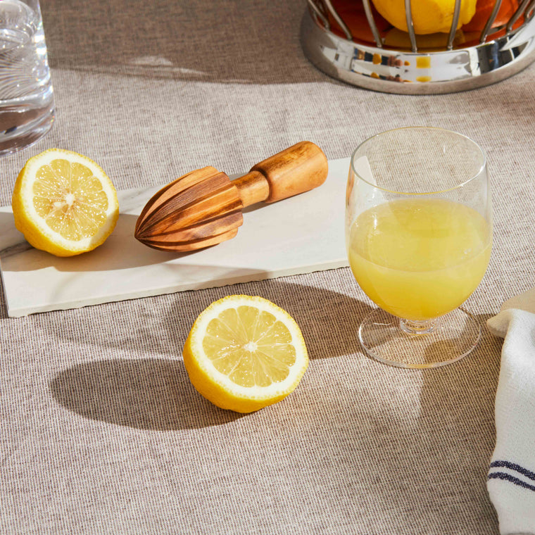 Moodbild der Zitronenpresse auf einem gedeckten Tisch vor Zitronen und Limetten