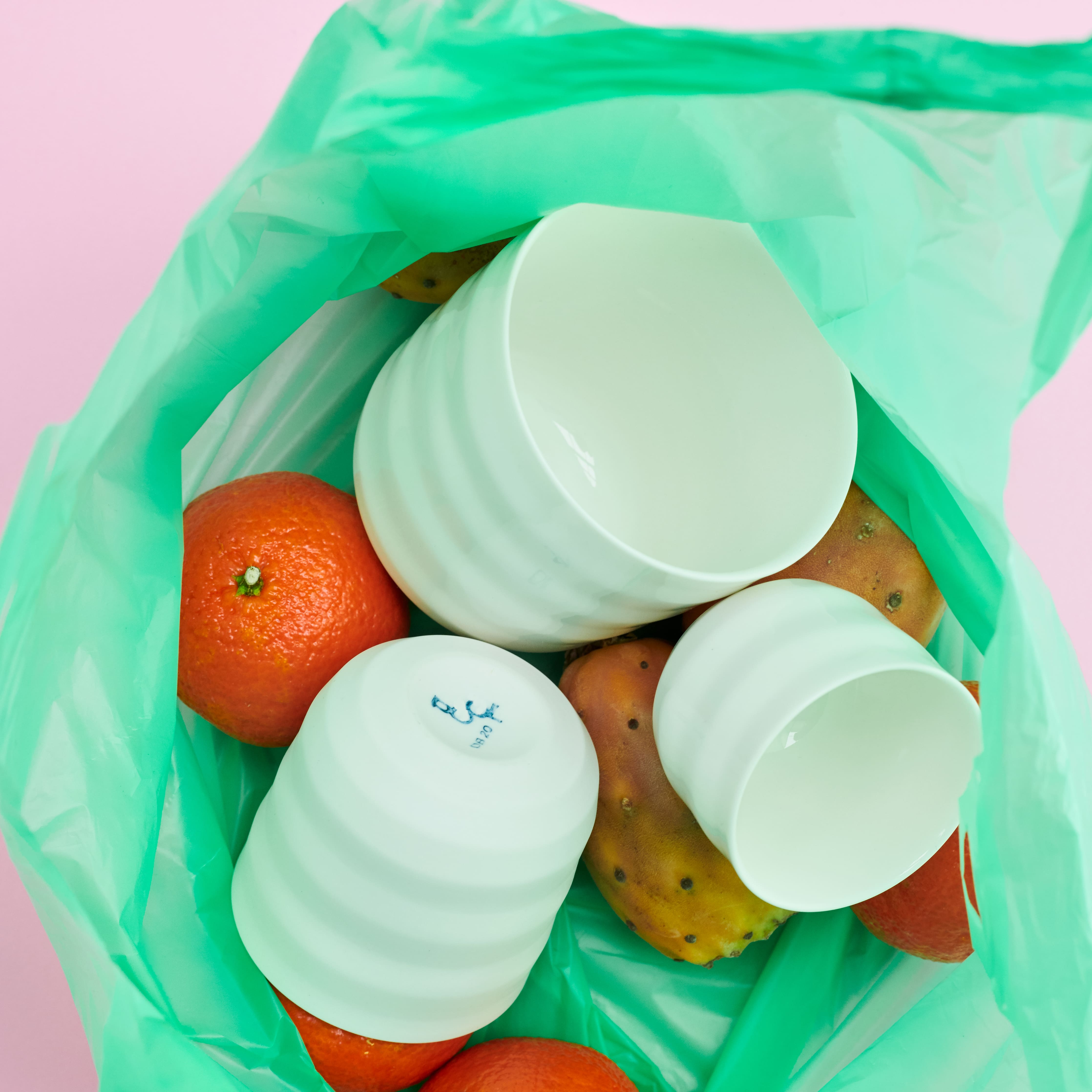 mood: Moodbild der drei Becher der DB20 Serie in einer grünen Einkaufstüte zusammen mit Mandarinen und Bananen