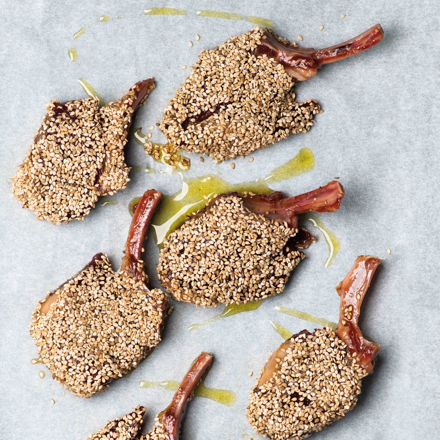 Lammkoteletts in Sesamkruste auf Backpapier mit Olivenöl