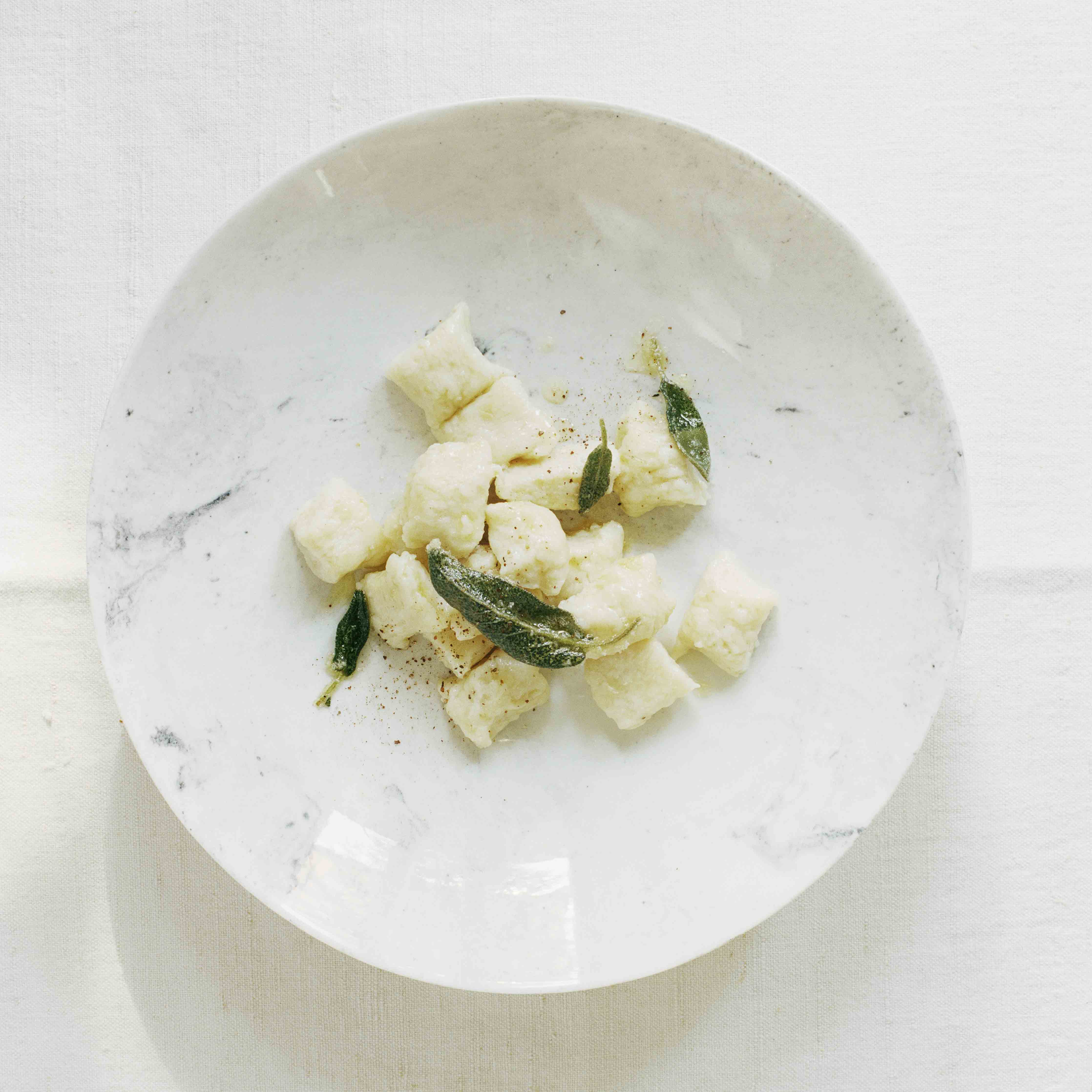 Selbstgemachte Pastinakengnocchi an Salbeibutter als Hauptgang serviert auf einem weissen Porzellanteller von Laurin Schaub