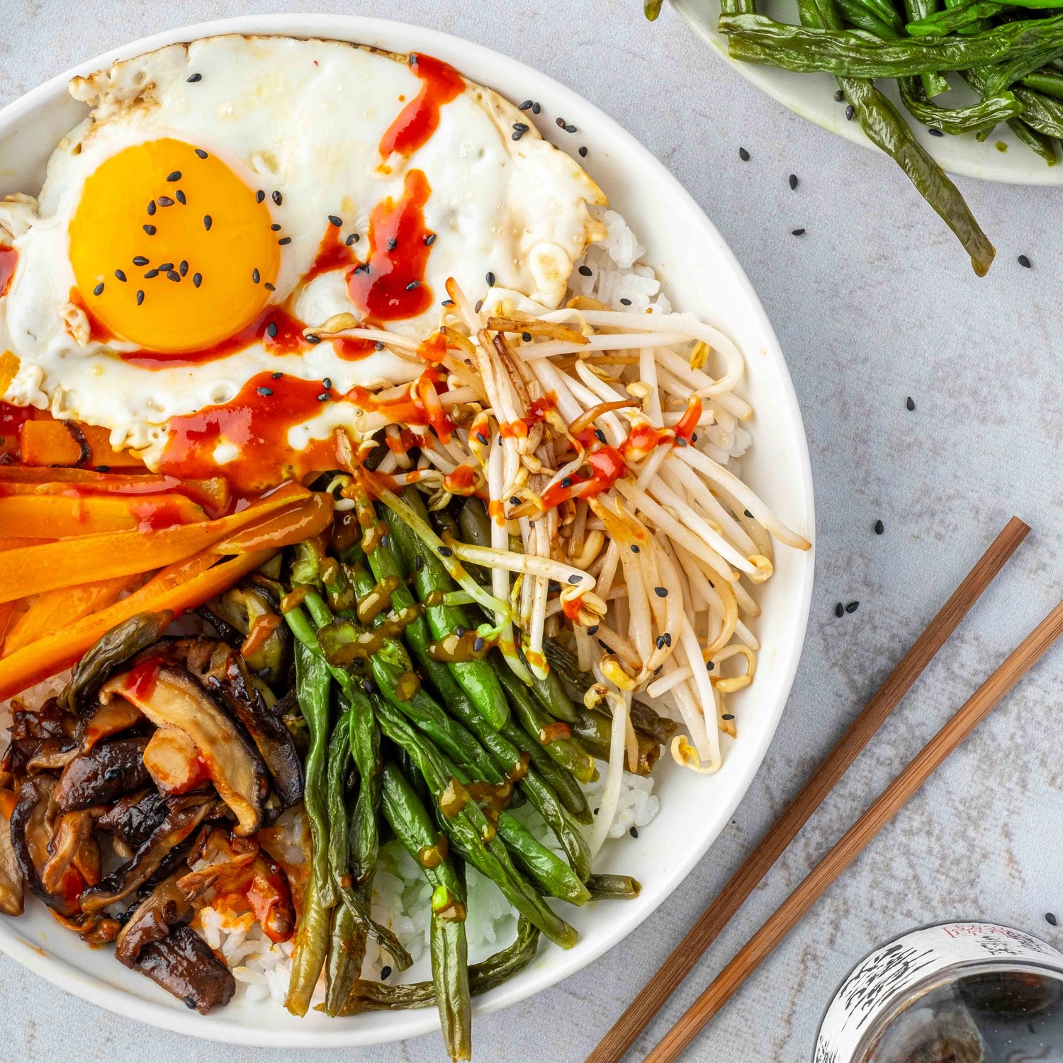 Koreanisches Dörrbohnengericht Bibimbap mit Spiegelei und schwarzem Sesam