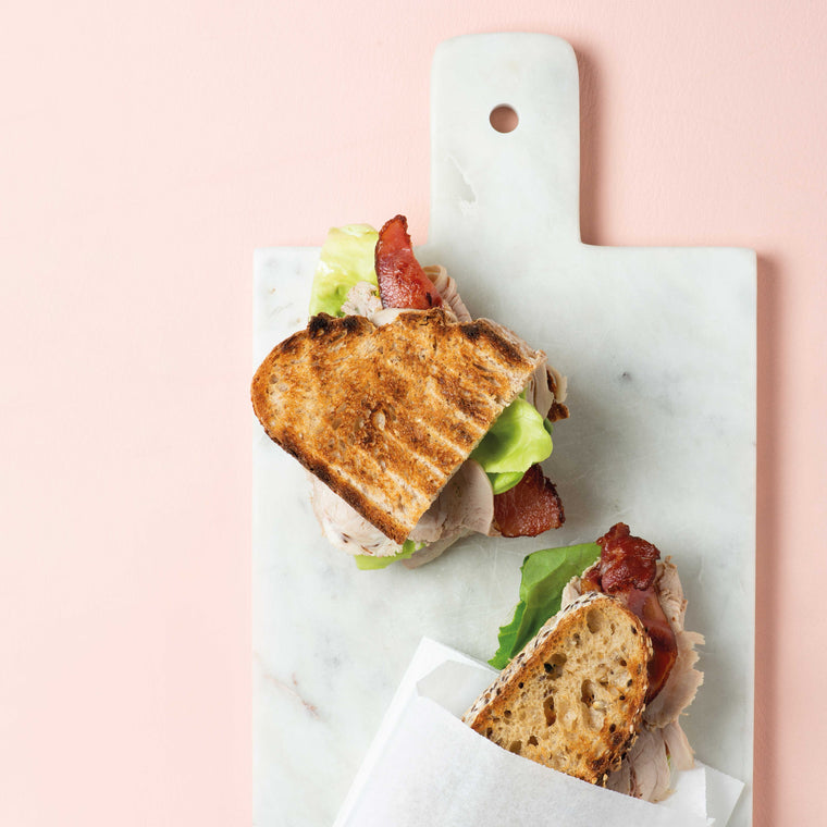 Sandwiches mit geröstetem Brot, Salat und Kalbsbraten auf rosa Untergrund