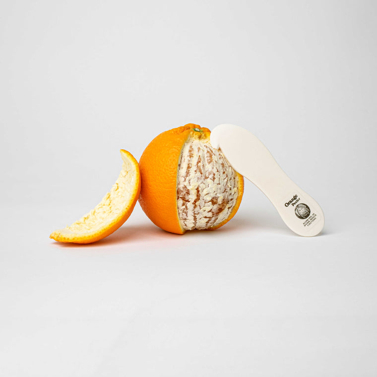 Moodbild des handgeschnitzten Orangenschälers vor einer halb geschälten Orange
